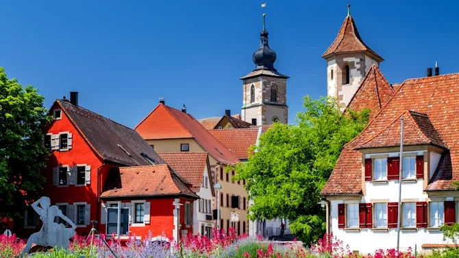 Blick auf historische Gebäude in Crailsheim mit roten Dächern, Kirchturm, Fachwerkarchitektur und grüner Umgebung. Das Bild wird auf der Standortseite Crailsheim von GARANT Immobilien verwendet und steht für den regionalen Immobilienmarkt, wirtschaftsstarke Wohnlagen und Immobilienberatung in Crailsheim, dem Hohenlohekreis und Schwäbisch Hall.