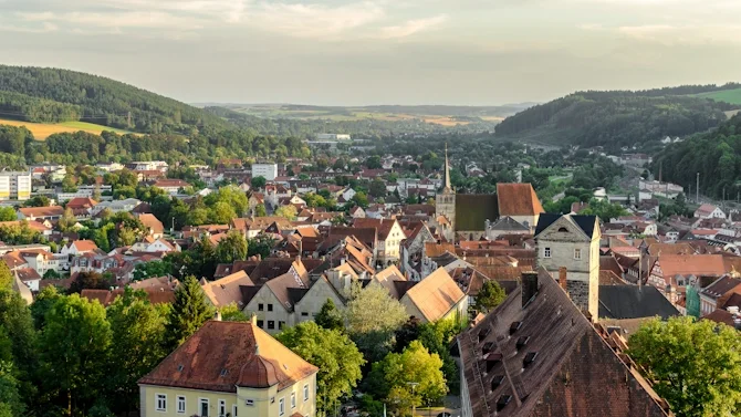Blick über Hof mit historischen Gebäuden, roten Dächern, Kirchturm und grüner Hügellandschaft im Hintergrund. Das Bild wird auf der Standortseite Hof von GARANT Immobilien verwendet und steht für den regionalen Immobilienmarkt, naturnahe Wohnlagen und Immobilienberatung in Hof, Bayreuth und den umliegenden Landkreisen in Oberfranken.