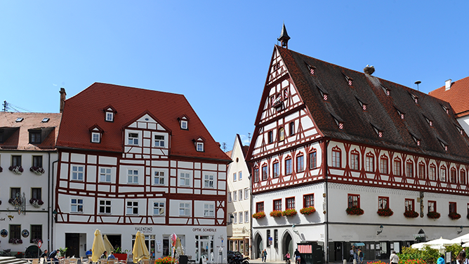 Blick auf den historischen Marktplatz in Nördlingen mit Fachwerkhäusern, roten Dächern, klassischer Altstadtarchitektur und blauem Himmel. Das Bild wird auf der Standortseite Nördlingen von GARANT Immobilien verwendet und steht für den regionalen Immobilienmarkt, historische Wohnlagen und Immobilienberatung in Nördlingen, Deiningen, Möttingen, Oettingen, Bopfingen und Harburg.