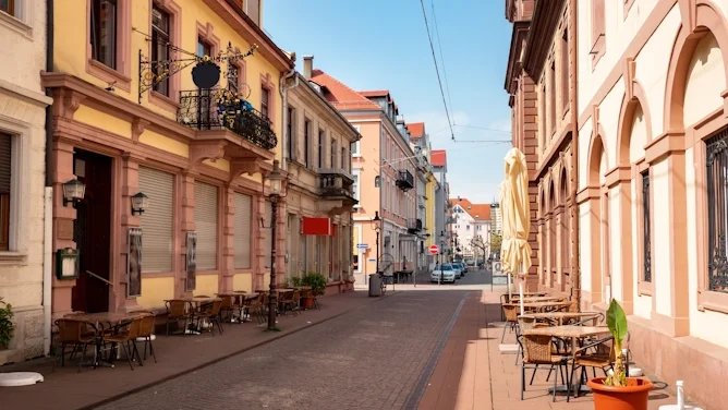 Blick in eine historische Straße im Ortenaukreis mit Altbaufassaden, Sandsteinarchitektur, Außengastronomie, gepflasterter Straße und warmem Stadtbild. Das Bild wird auf der Standortseite Ortenaukreis von GARANT Immobilien verwendet und steht für den regionalen Immobilienmarkt, historische Wohnlagen und Immobilienberatung in Offenburg, Oberkirch, Lahr, Rastatt und Umgebung.