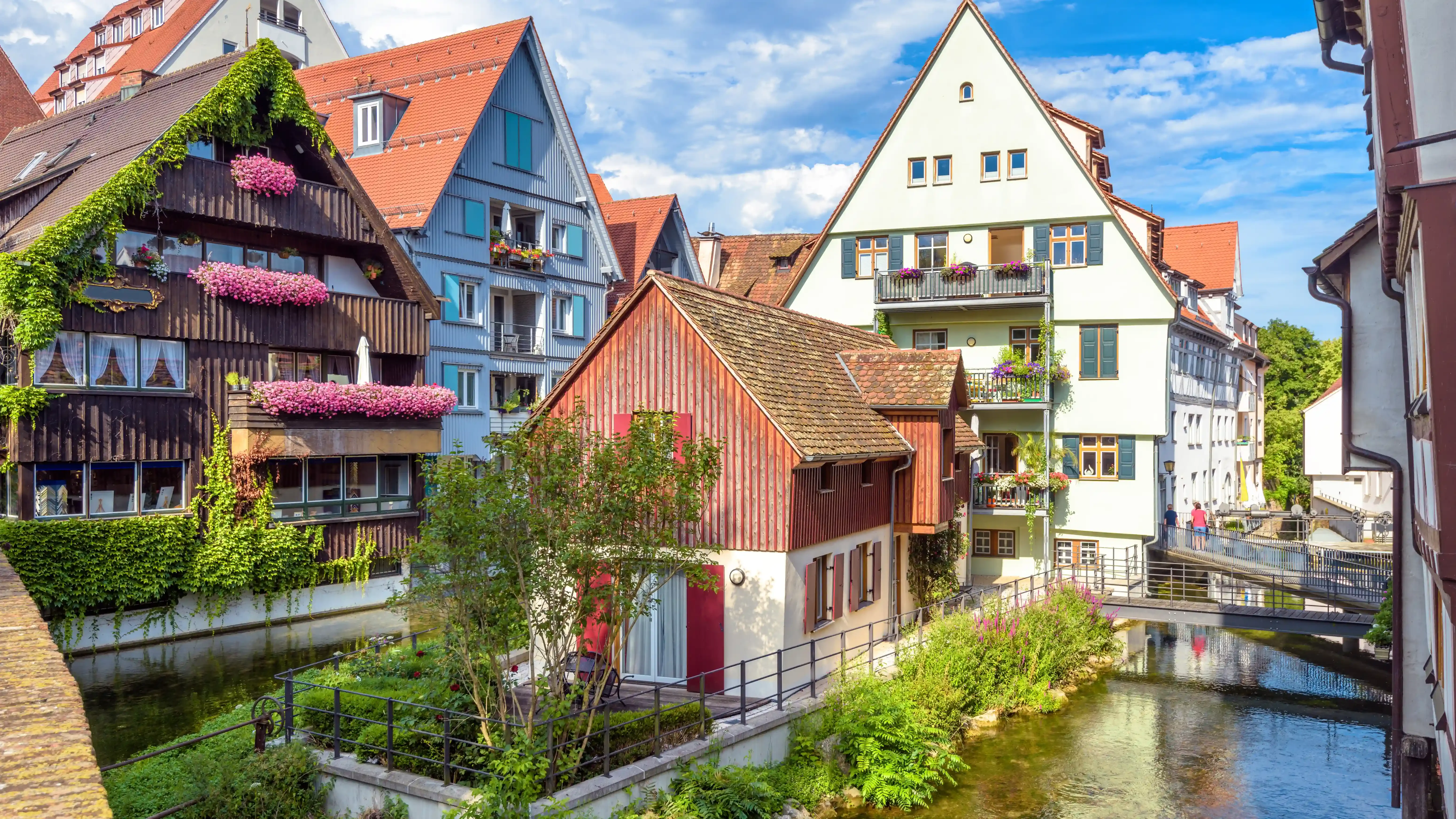 Blick auf das historische Fischerviertel in Ulm mit Fachwerkhäusern, roten Dächern, Wasserlauf, Brücke, grünen Pflanzen und blauem Himmel. Das Bild wird auf der Standortseite Ulm und Neu-Ulm von GARANT Immobilien verwendet und steht für den regionalen Immobilienmarkt, historische Wohnlagen und Immobilienberatung in Ulm, Neu-Ulm, Alb-Donau-Kreis, Biberach, Heidenheim und Günzburg.