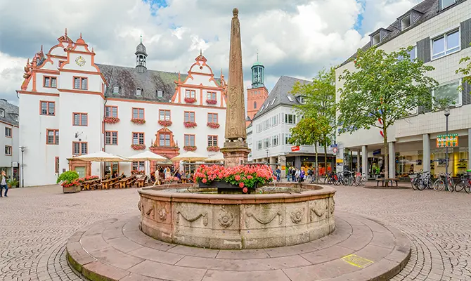 Blick auf einen historischen Platz in Darmstadt mit Brunnen, hellen Fassaden, klassischer Architektur und belebter Innenstadt. Das Bild wird auf der Standortseite Darmstadt von GARANT Immobilien verwendet und steht für den regionalen Immobilienmarkt, attraktive Wohnlagen und Immobilienberatung in Darmstadt, der Bergstraße und Darmstadt Dieburg.