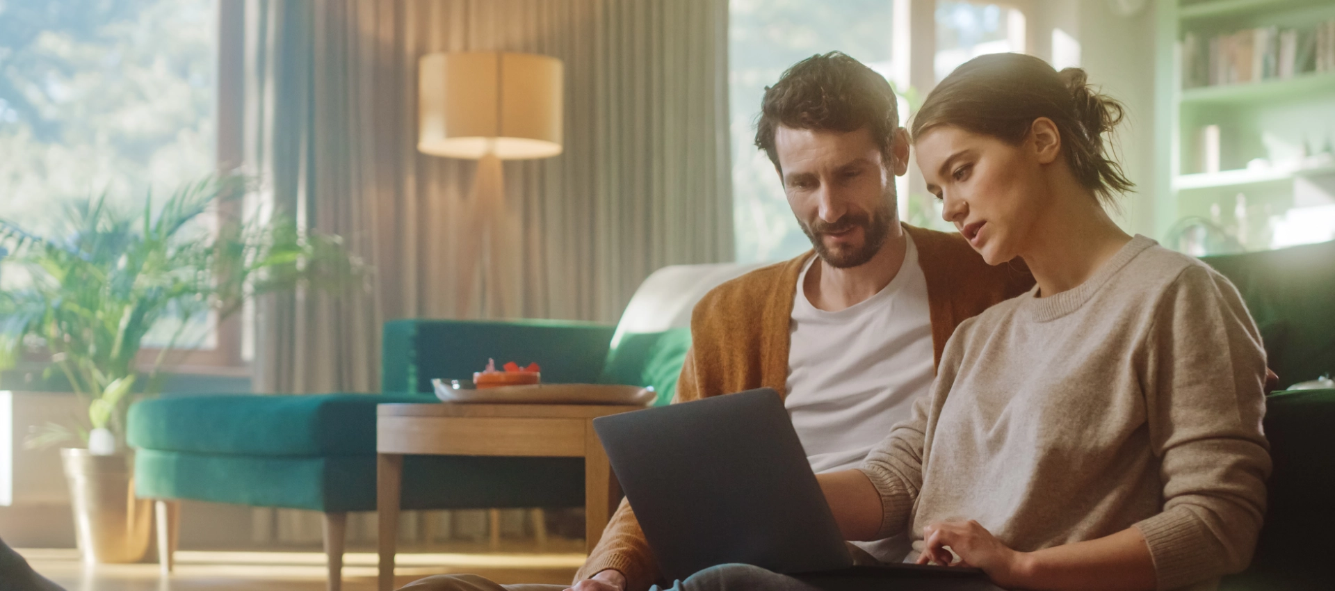 Ein Paar sitzt gemeinsam in einem hellen Wohnraum und schaut auf einen Laptop. Das Bild wird auf der Suchassistenten-Seite von GARANT Immobilien verwendet und steht für die digitale Unterstützung bei der Suche nach passenden Immobilienangeboten.